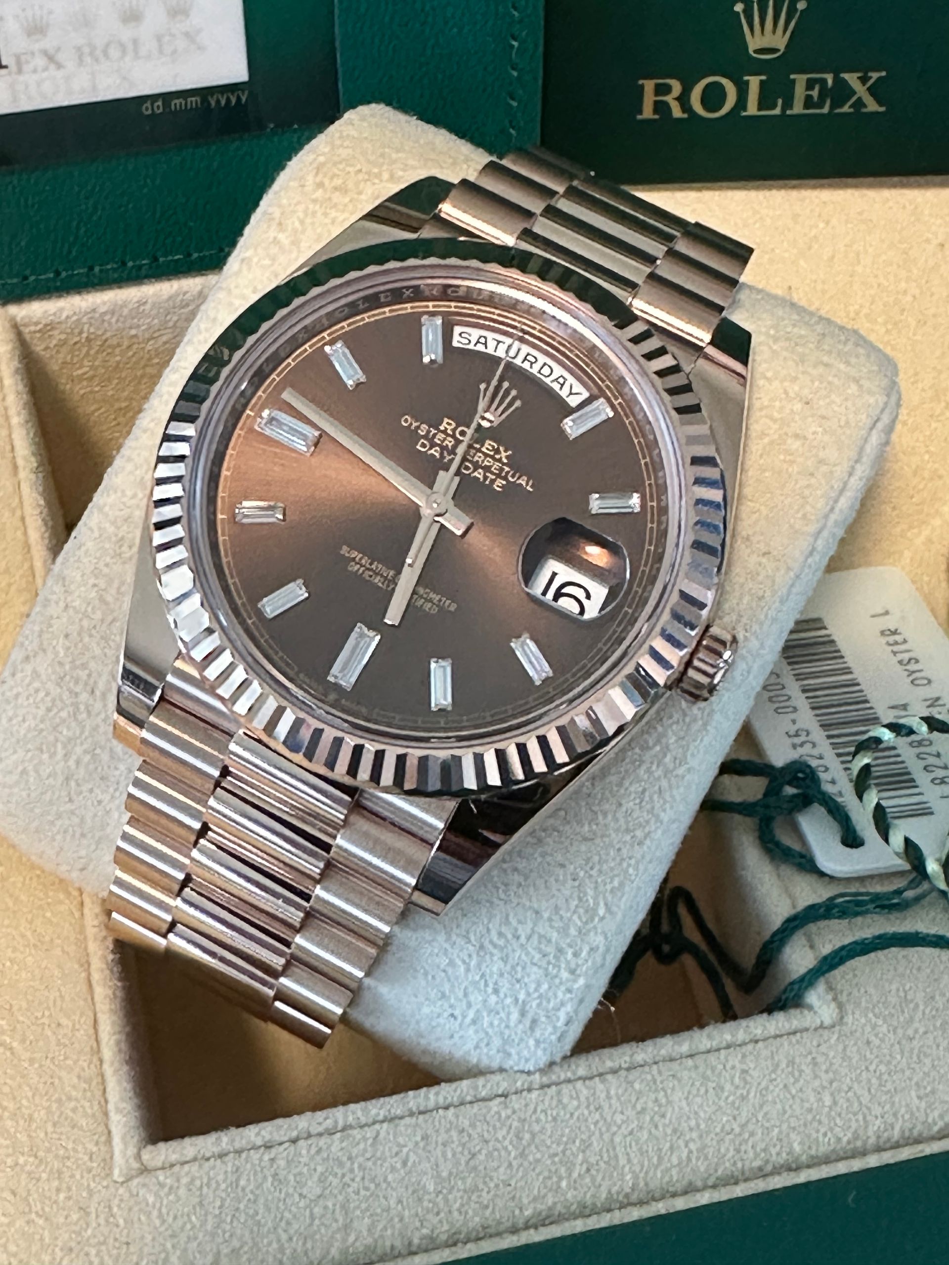 A rolex watch is sitting on top of a white cushion.