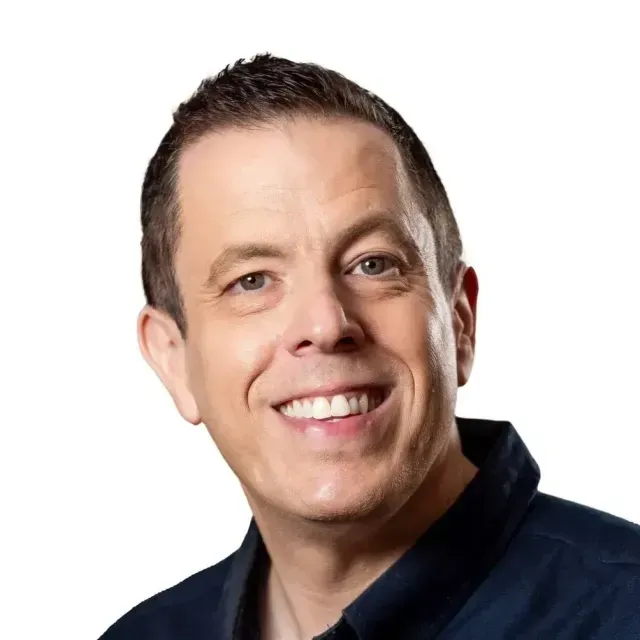 A man in a blue shirt is smiling for the camera