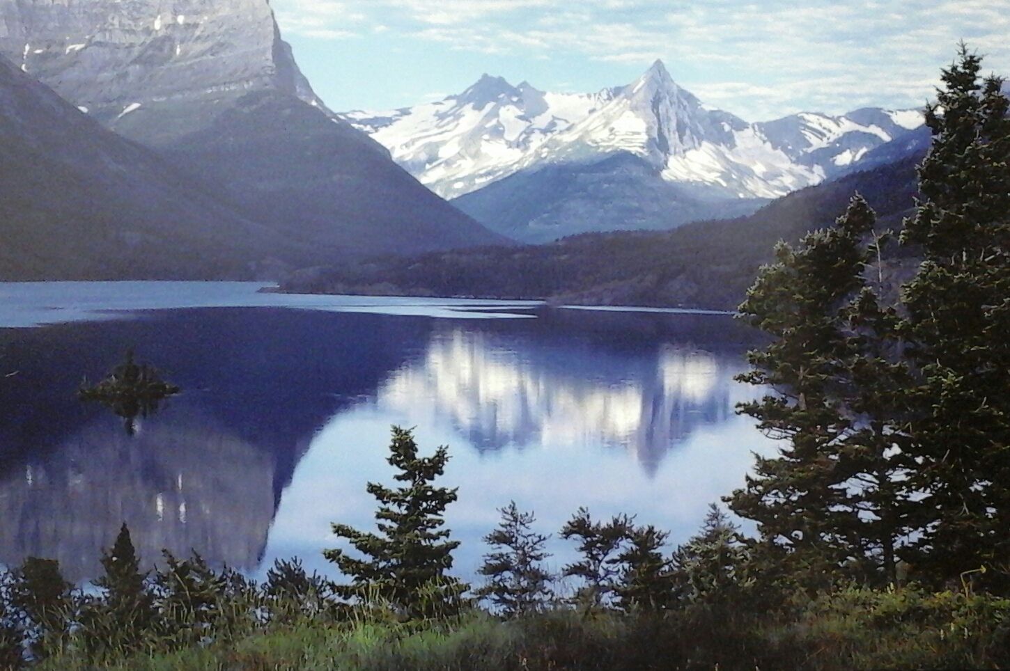 A lake with mountains in the background and trees in the foreground