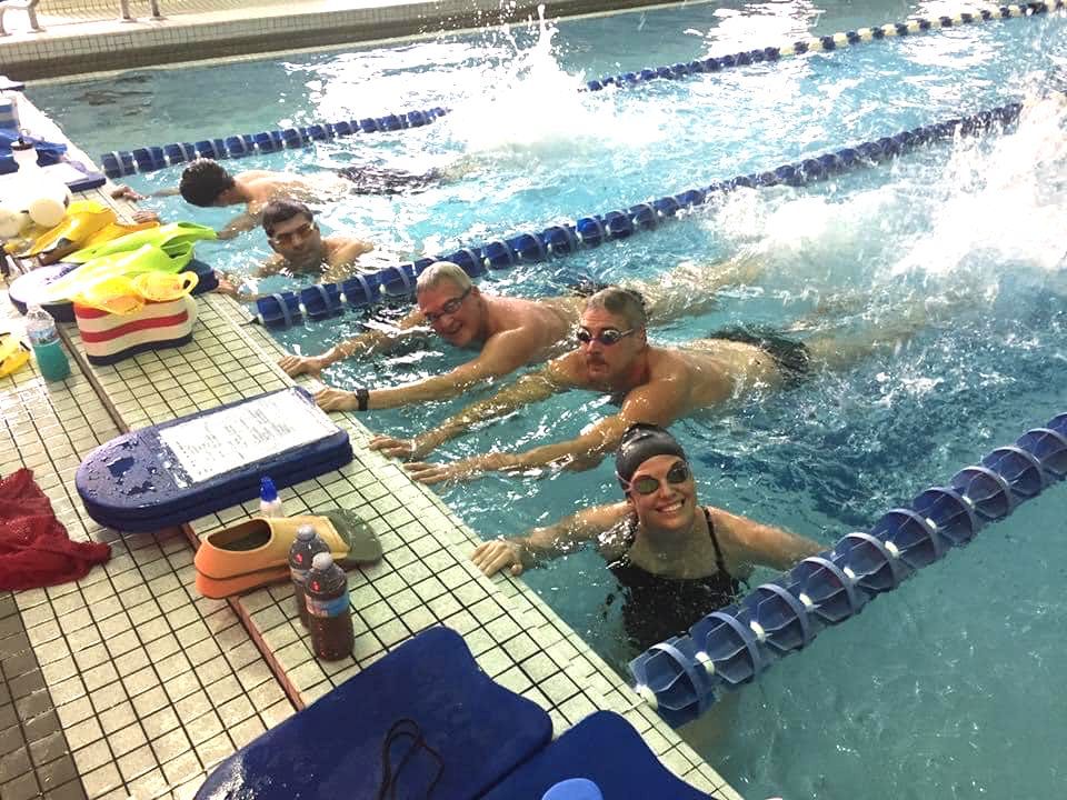 A group of people are swimming in a swimming pool.