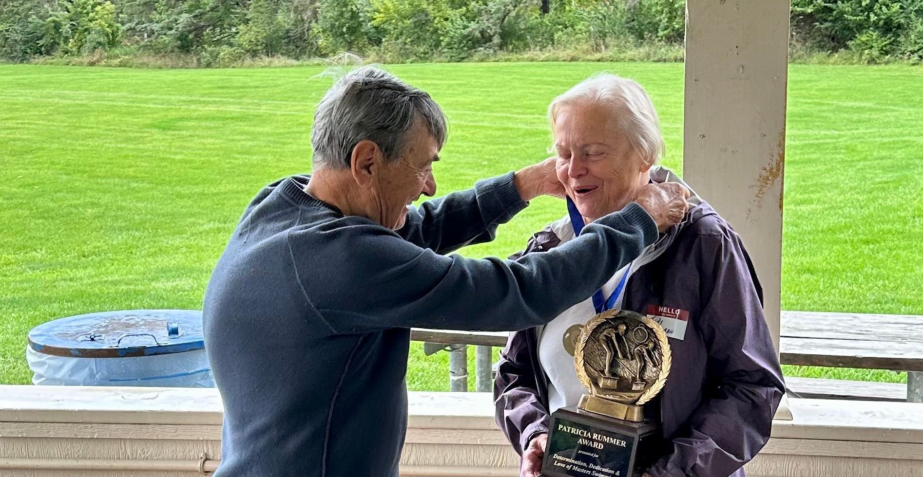 A man is putting a medal on another man 's neck.