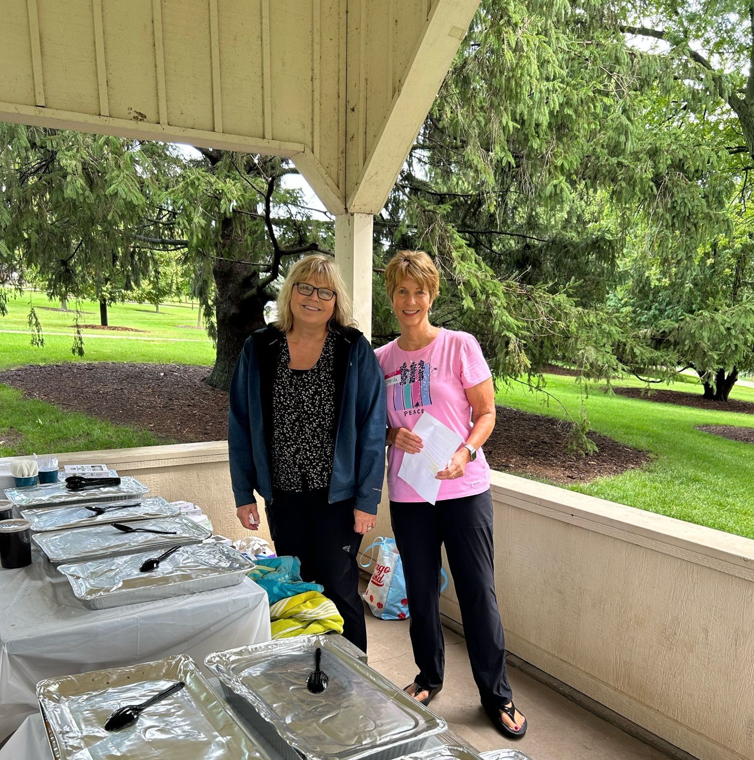 Two women standing next to each other in front of a buffet table