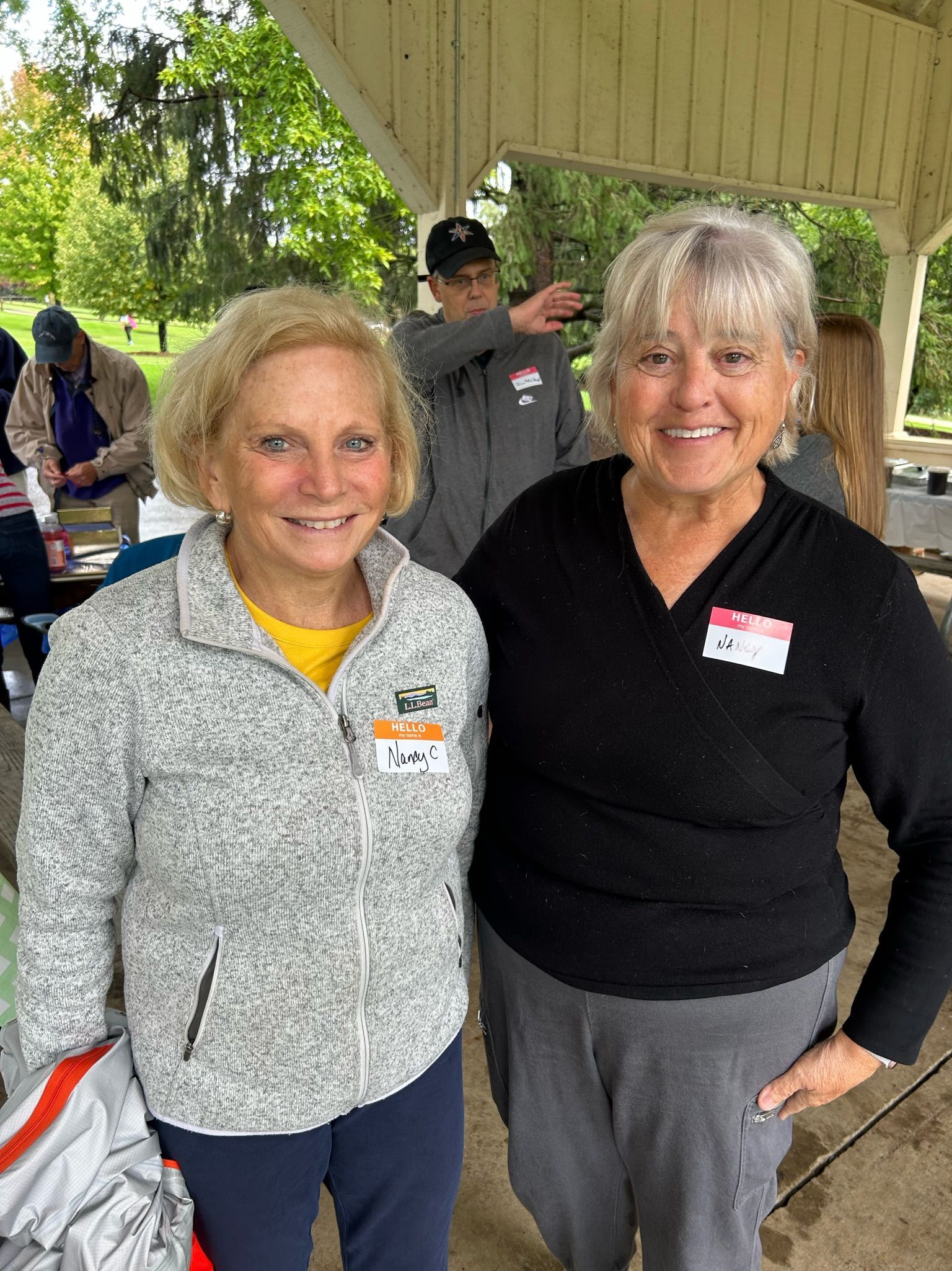 Two women are posing for a picture together in a park.