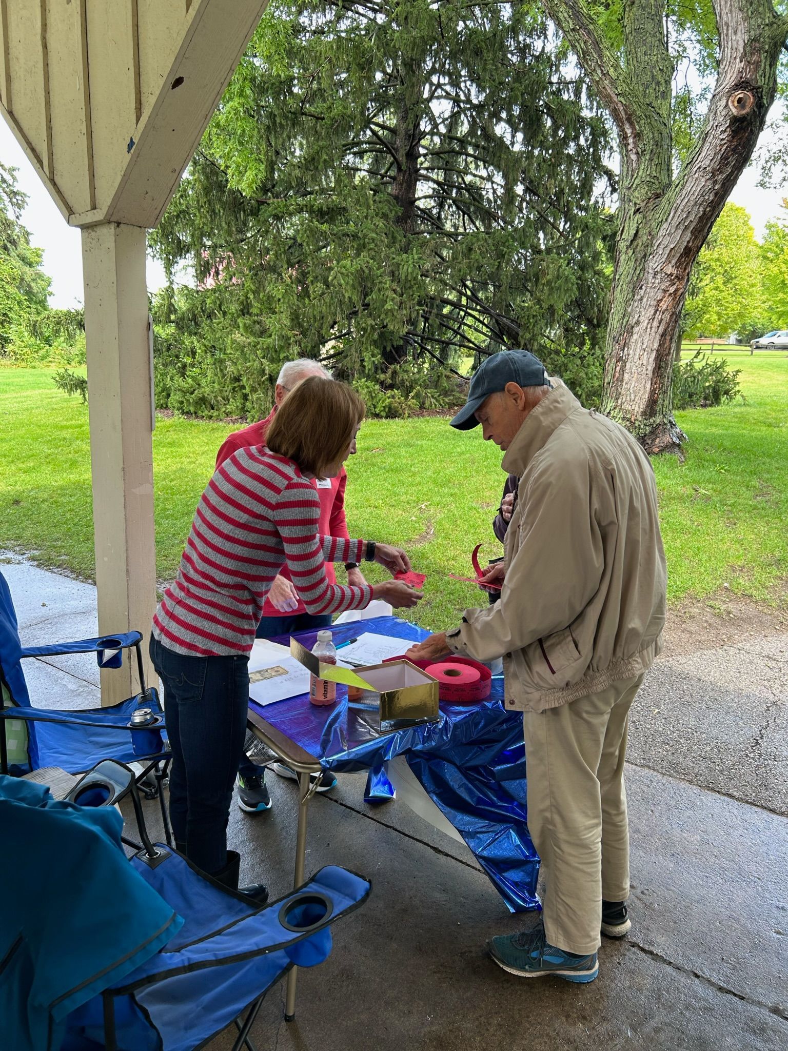 A group of people are standing around a table in a park.