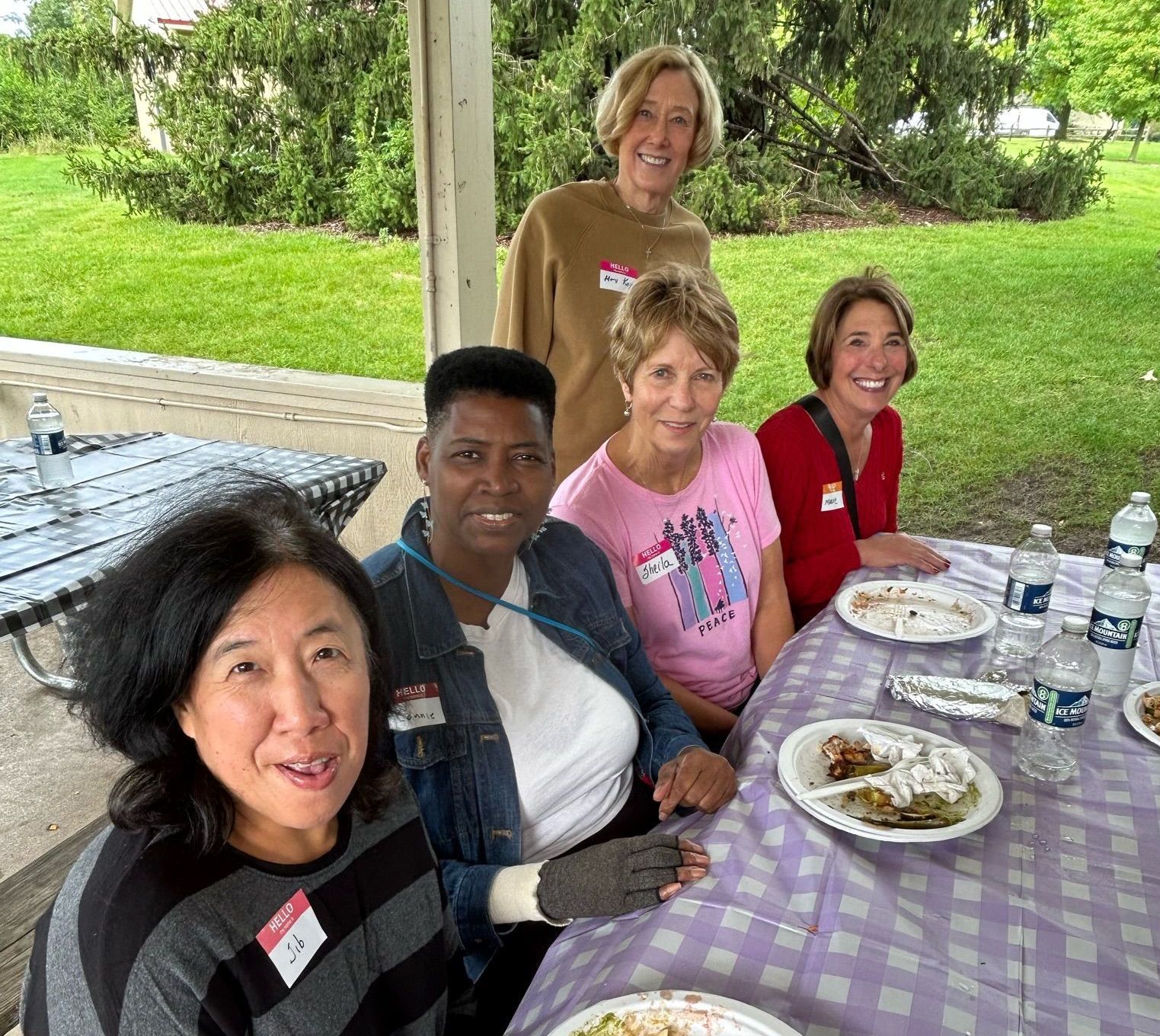 A group of women are sitting at a picnic table with plates of food.