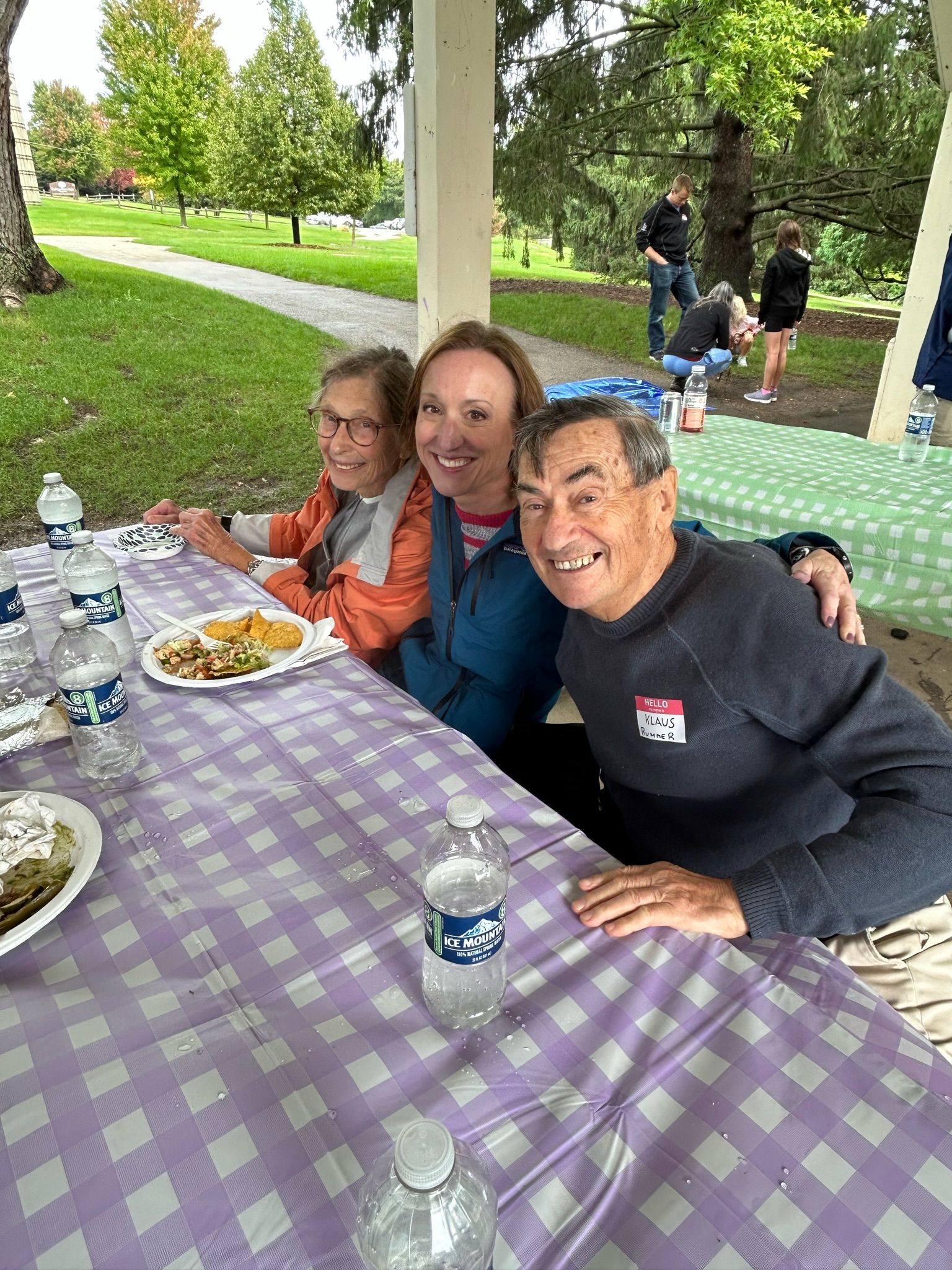 A group of people are sitting at a picnic table in a park.