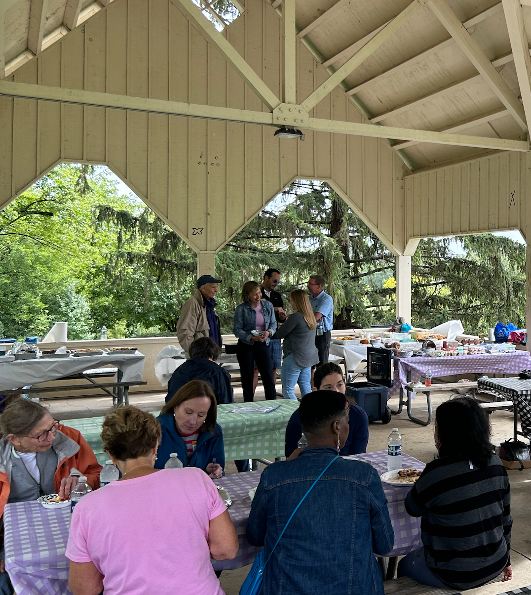 A group of people are sitting at tables in a pavilion