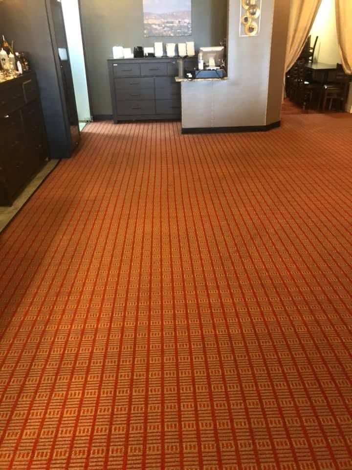 Red carpeted hotel lobby with a reception desk and decorative lighting.
