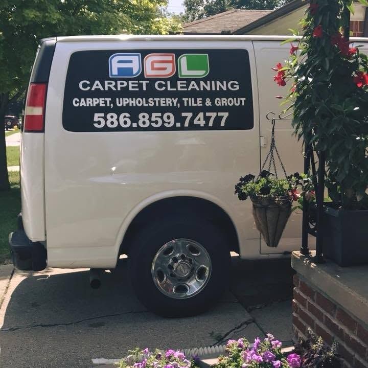 White AGL Carpet Cleaning van parked on a driveway with visible business name and phone number.