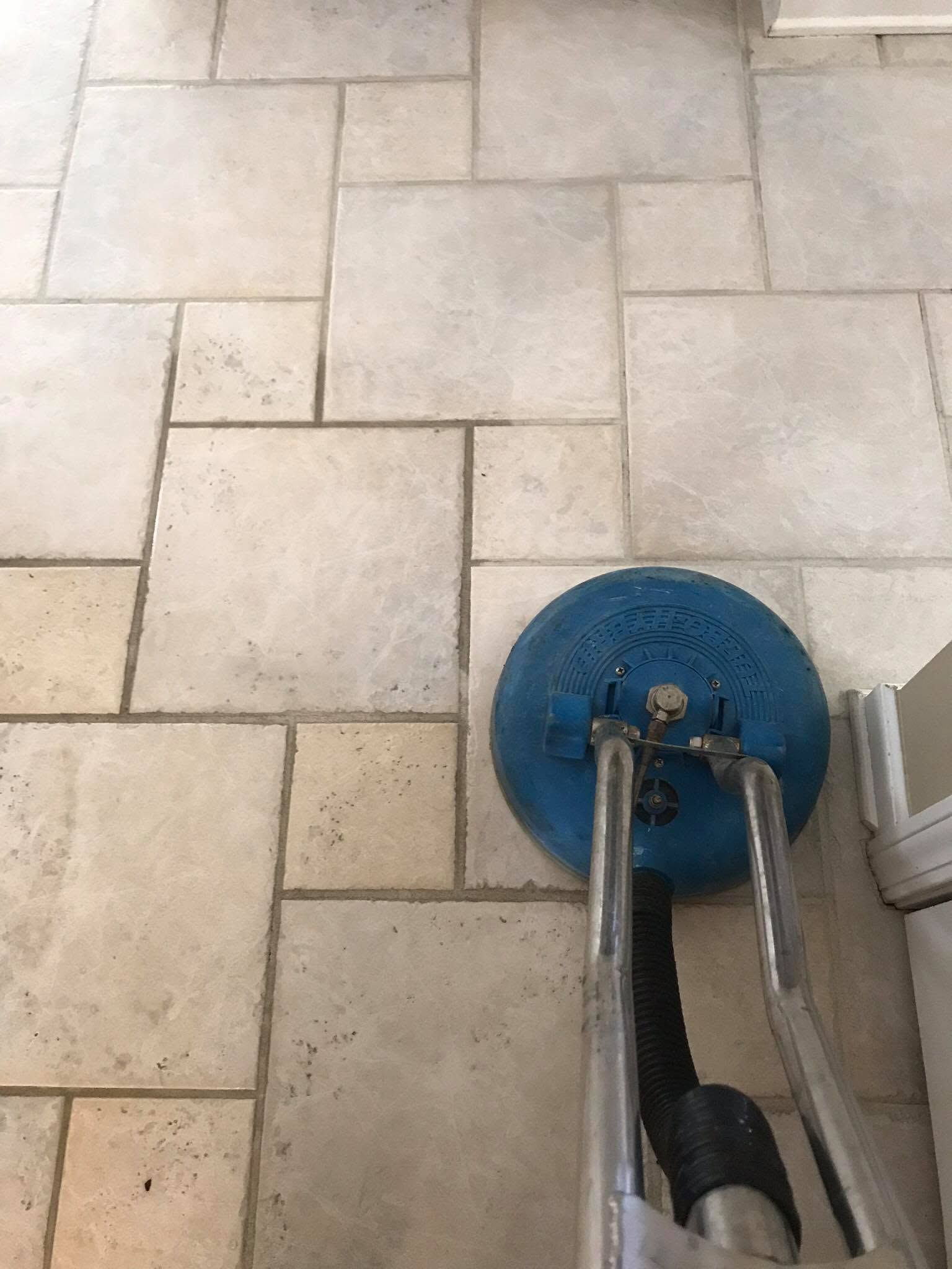 Blue floor-cleaning machine on beige tiled pavement, viewed from above.