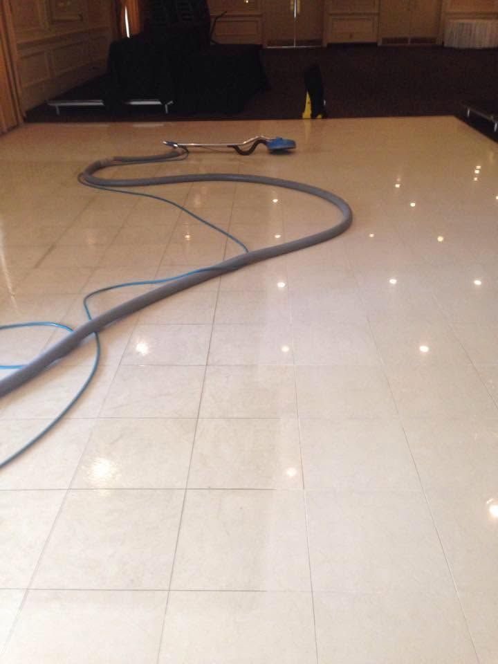 Vacuum hose coiled across a shiny tiled floor near a stage or wall
