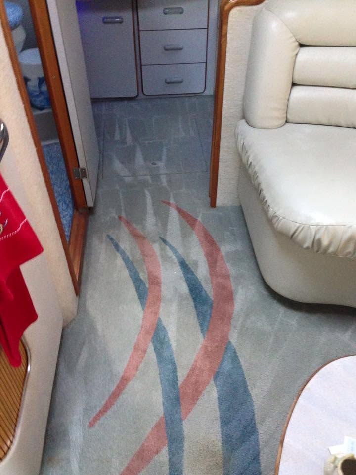 Narrow RV aisle with beige seating and gray carpet featuring red and blue wave patterns.