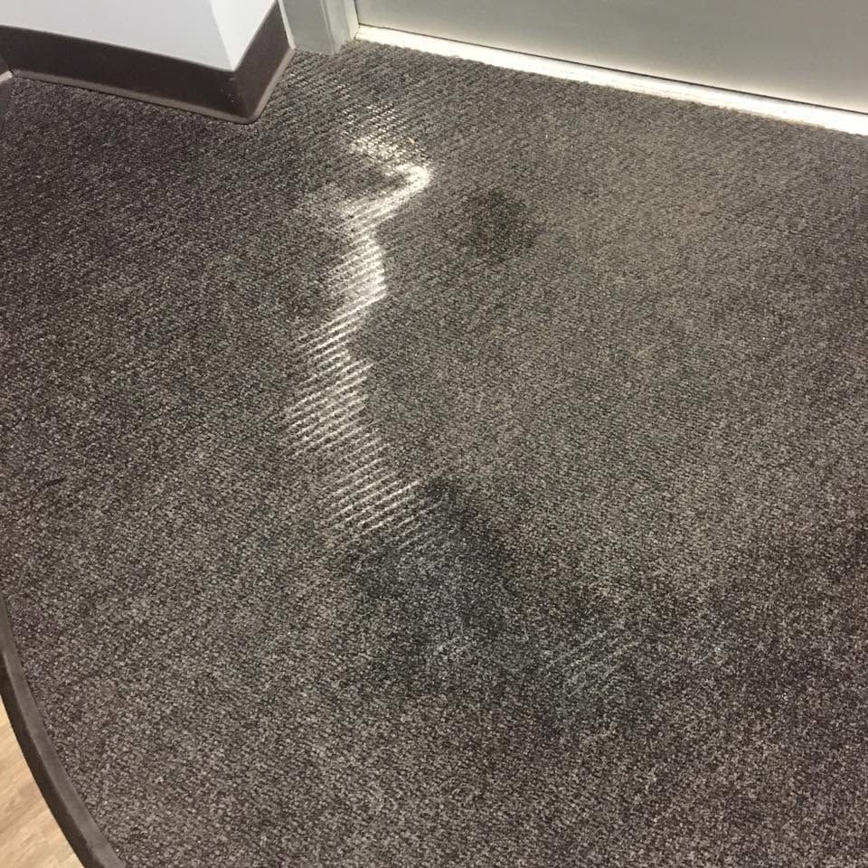 Dark carpet with a lighter, wavy stain or water mark near the top left corner.
