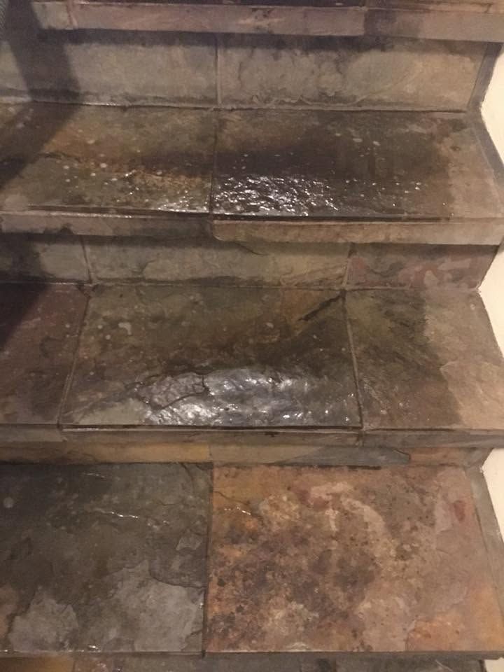 Wet stone steps with dark stains and patches of moss or dirt in dim light