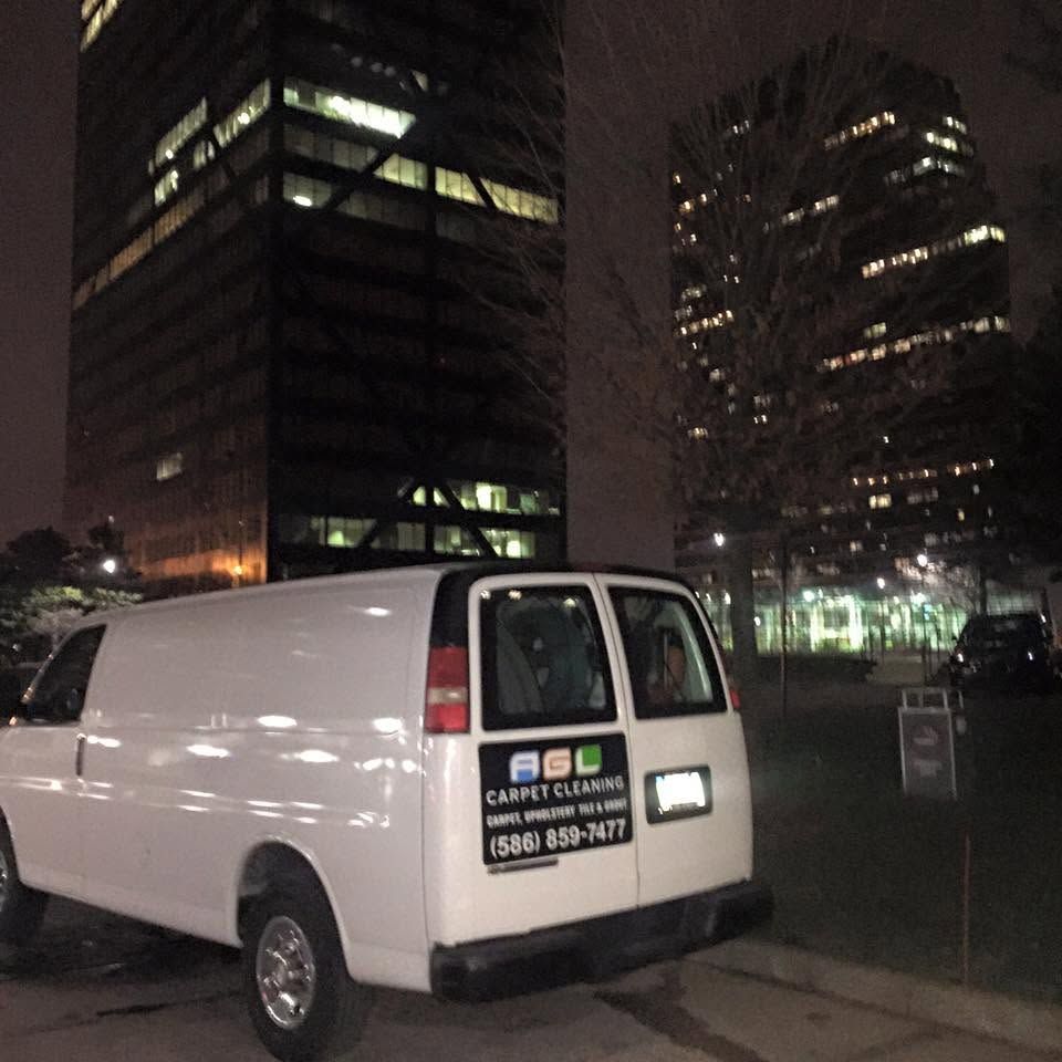 White cargo van parked at night in front of lit office buildings, with a company sign on the rear door