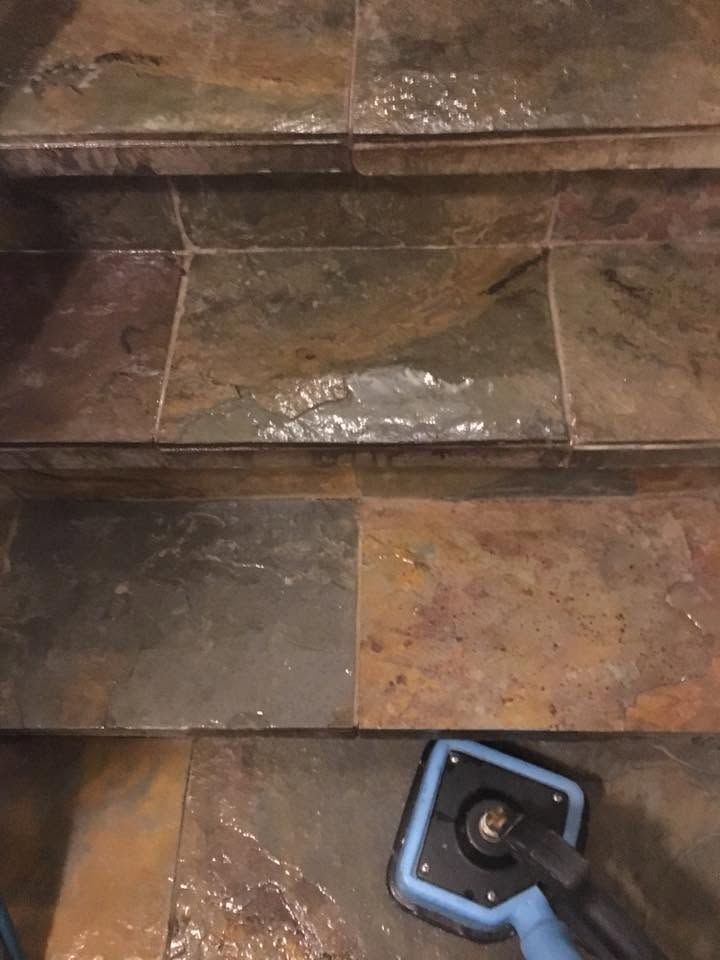 Wet tiled steps being cleaned with a blue scrub brush and water.