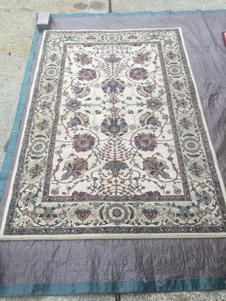 Patterned beige and blue area rug laid flat on a gray surface