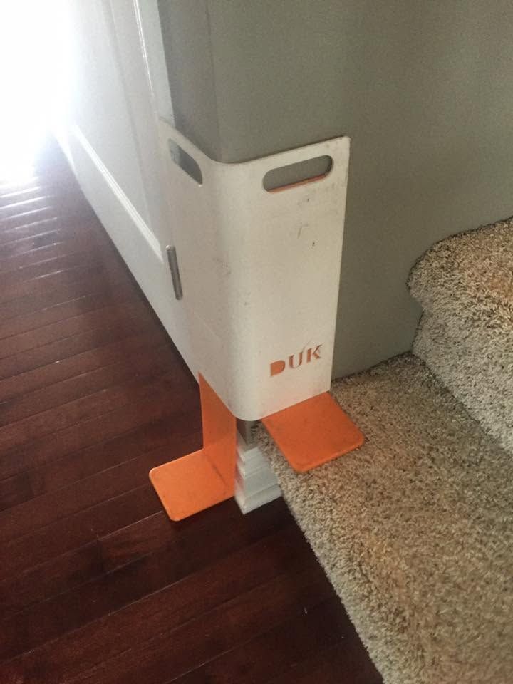 White and orange corner guard on hardwood floor beside a carpeted stair and wall corner