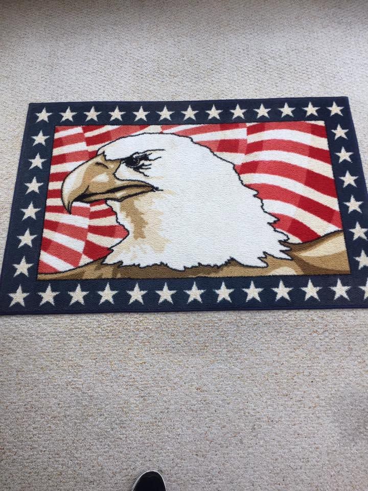 Eagle head rug with red-and-white stripes and a blue star border on carpet.