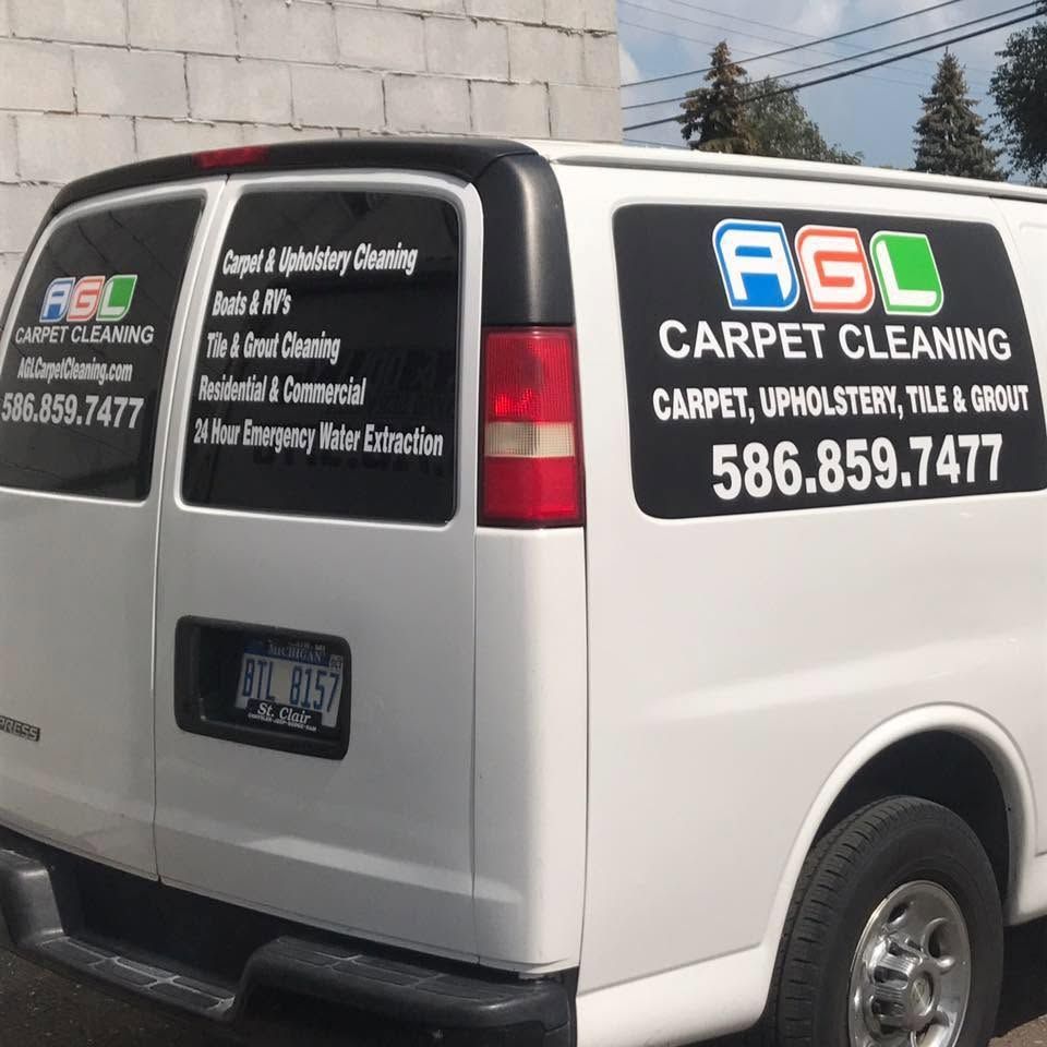 White A.G.L Carpet Cleaning van parked beside a wall