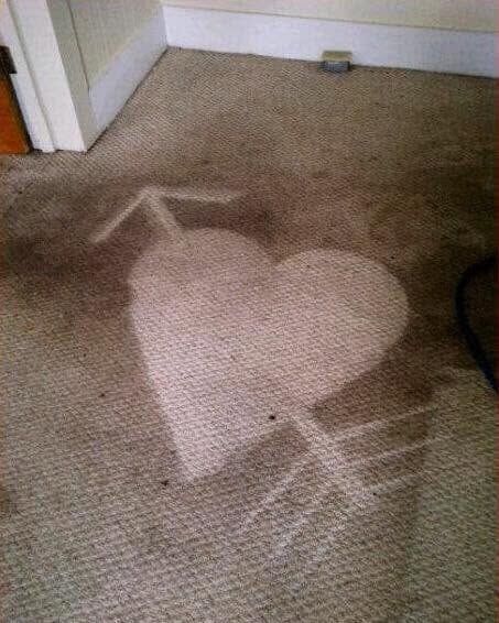 Beige carpet with a large heart-shaped stain near a doorway and wall corner