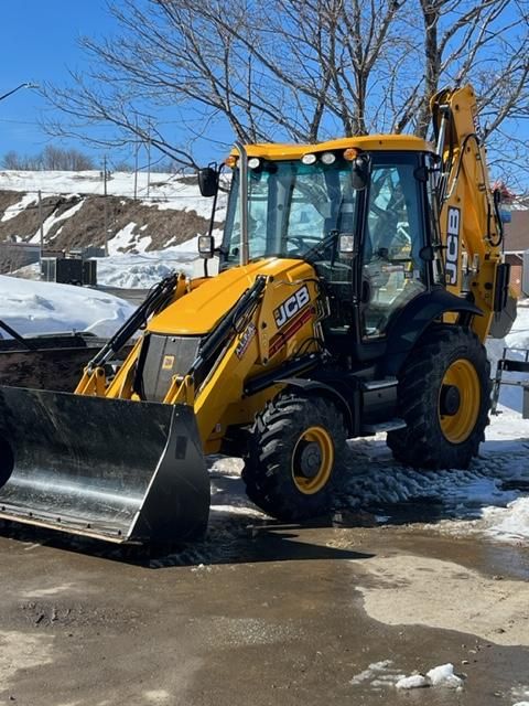 Yellow JCB backhoe loader parked outside on a sunny day.