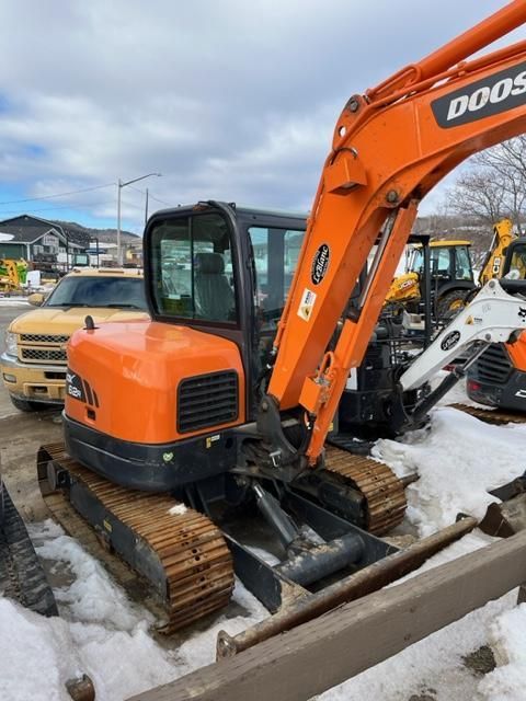 Orange Doosan excavator parked on snowy ground.