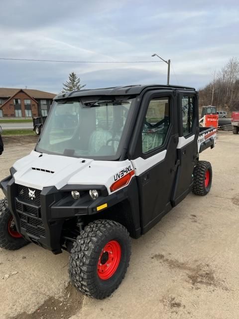 White and black Bobcat utility vehicle with red wheels parked outside.