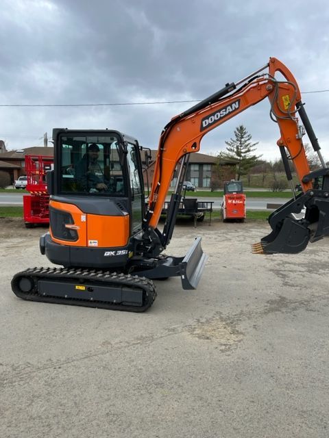 Orange Doosan mini excavator on a paved lot.