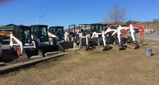 Bobcat construction equipment parked on a grassy lot under a blue sky.