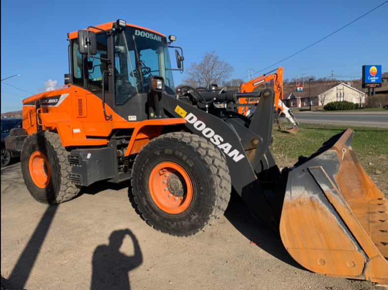 Orange Doosan wheel loader parked outdoors on a sunny day.