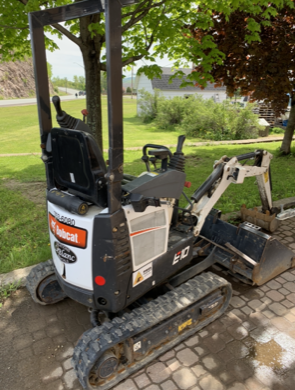 Bobcat E10 mini excavator on a paved surface, black and white, outdoors.