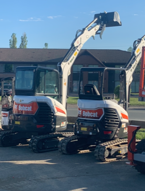 Two white Bobcat excavators parked outdoors.