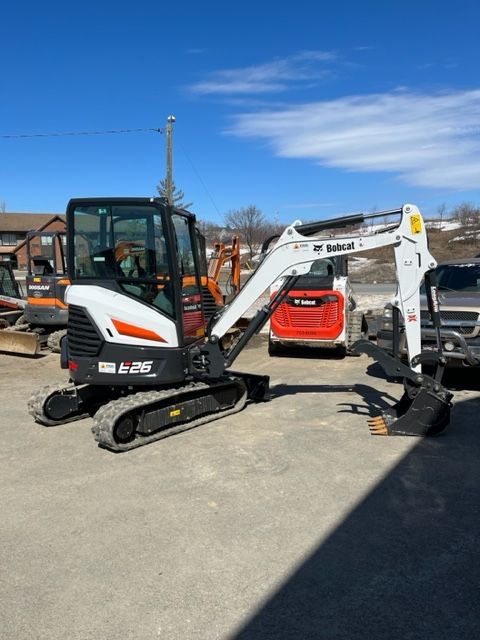White Bobcat excavator on a paved lot on a sunny day.
