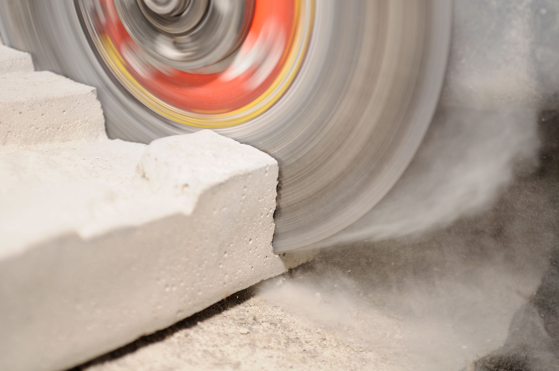 A circular saw cutting a light-colored brick, producing dust.