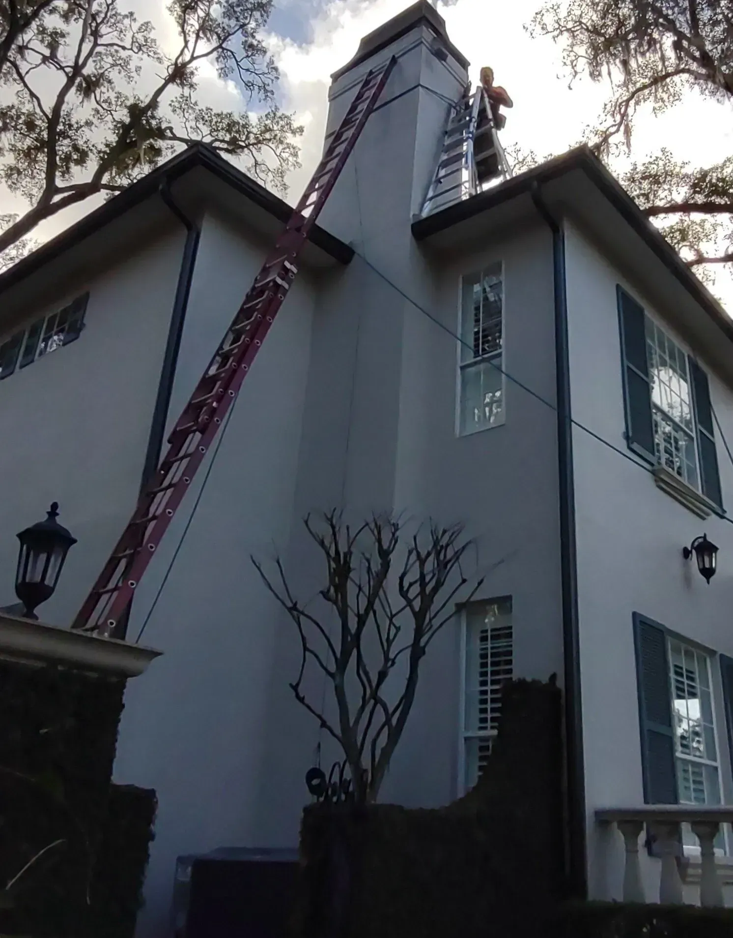 A man on a ladder on top of a white house