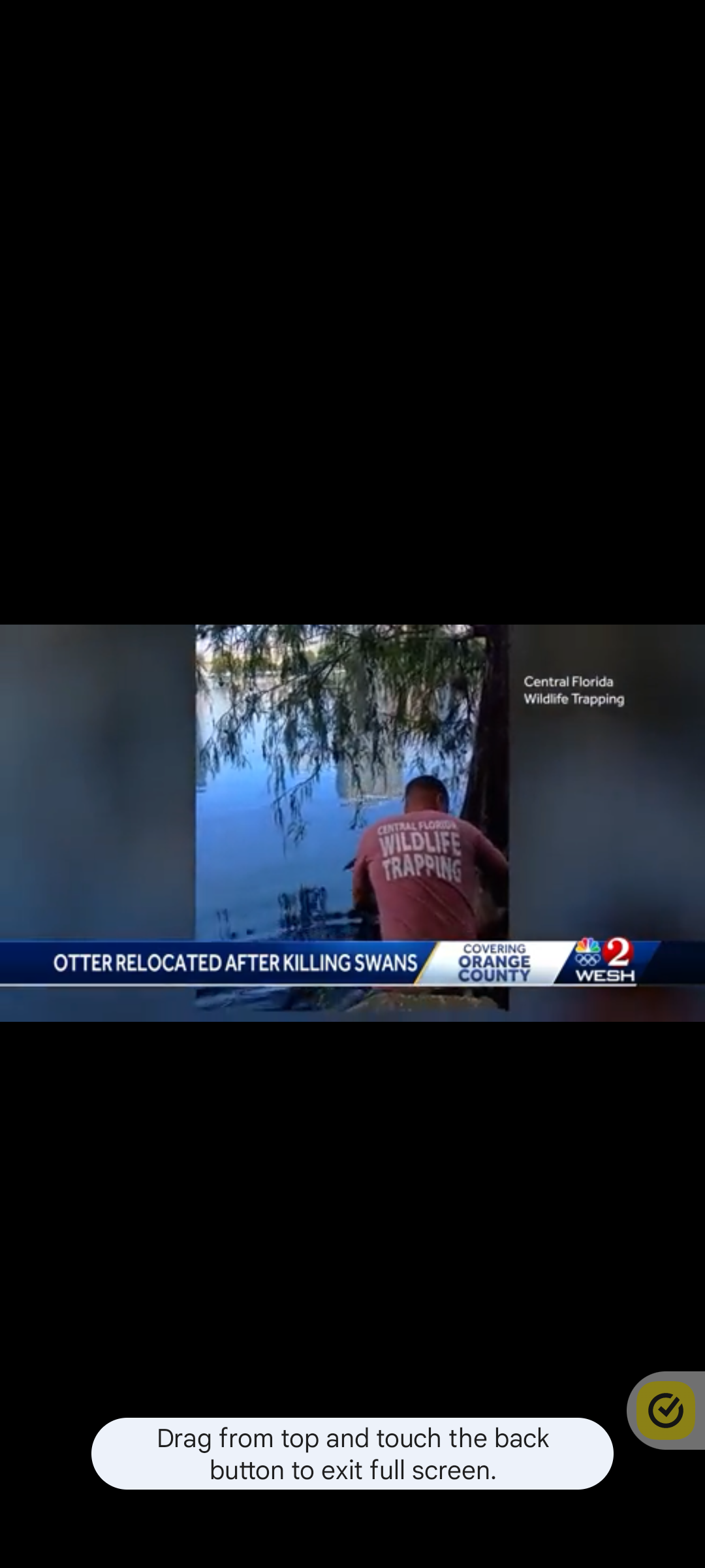 A man in a red shirt is standing in front of a flooded building.