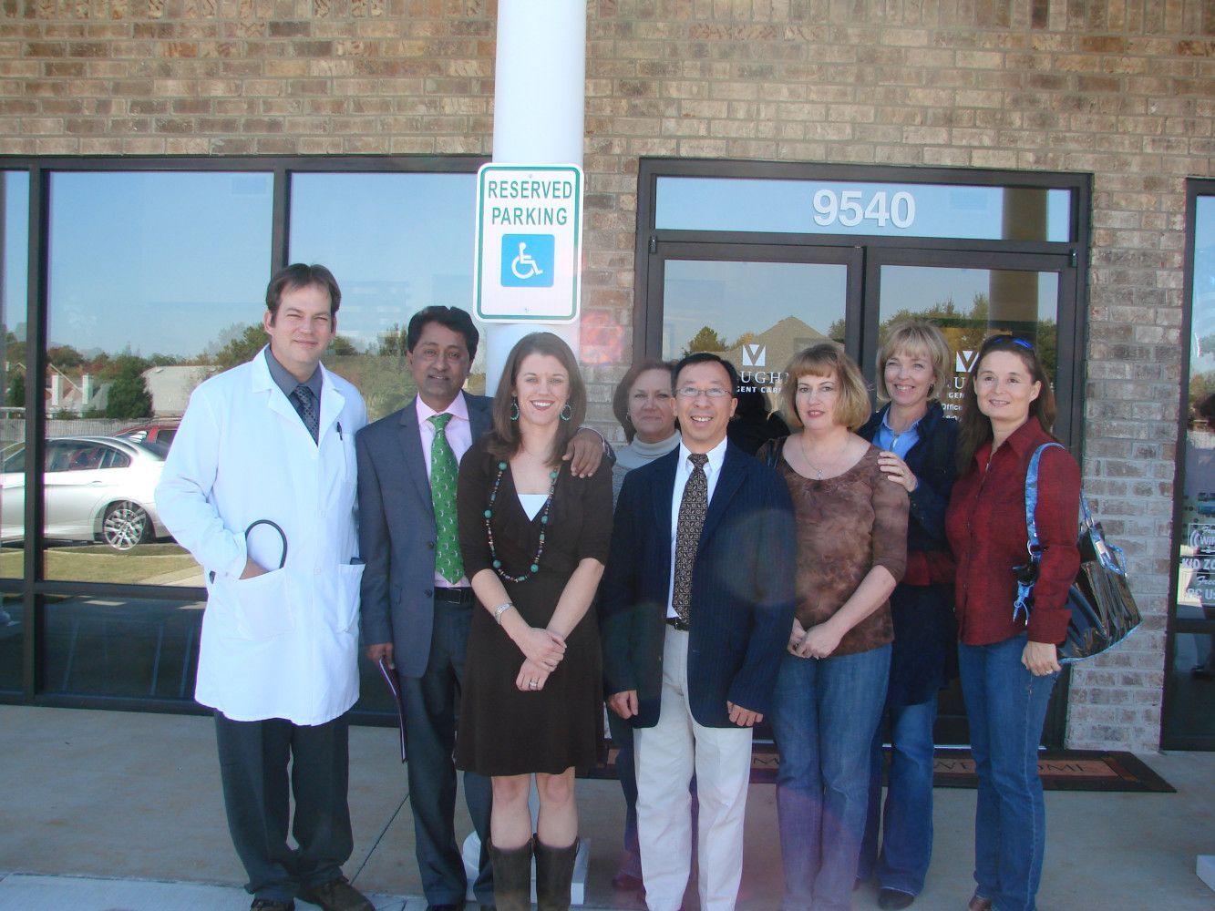 A group of people standing in front of a building with a handicapped parking sign