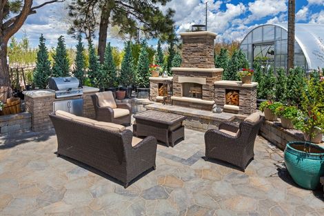Outdoor sitting area with stainless grill, light painted brick and fireplace area with stone oven and outdoor wicker seating