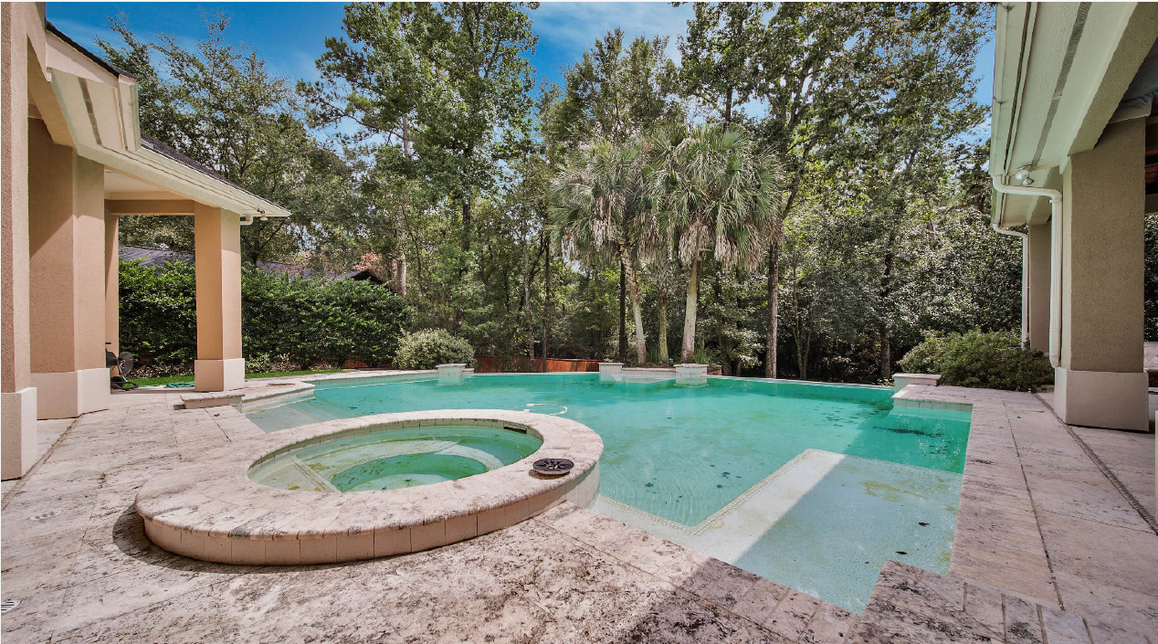 Backyard pool and hot tub beside a patio, surrounded by trees and greenery