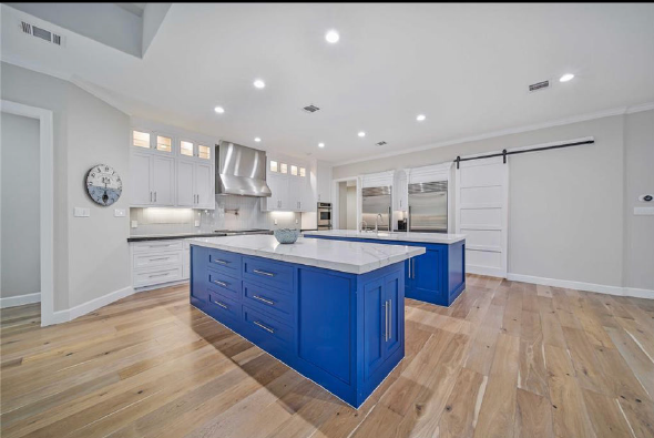 Bright modern kitchen with blue island, white cabinets, stainless appliances, and hardwood floors