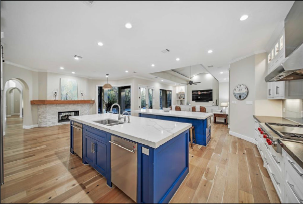 Bright modern kitchen with blue island, white cabinets, wood floors, and stainless-steel appliances