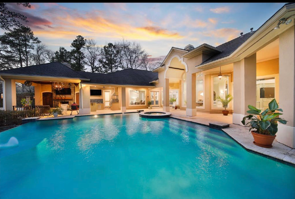 Luxury home patio with turquoise pool at sunset and warm lit columns