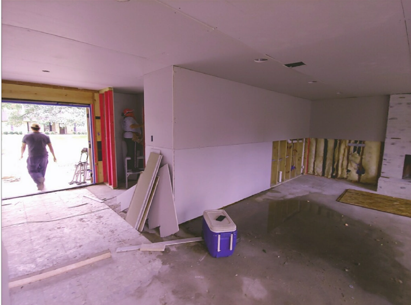 Bare garage interior with open door, one person outside, cooler and boards against the wall.
