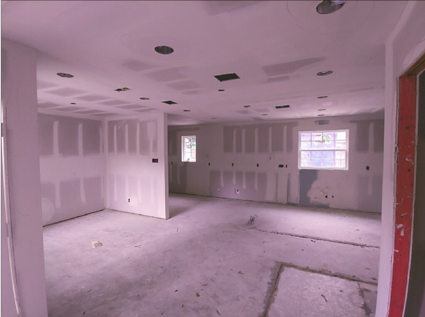 Empty unfinished room with drywall, bare floor, and recessed ceiling lights.