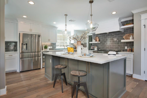 Modern kitchen with gray island, stainless steel appliances, white cabinets, and two stools