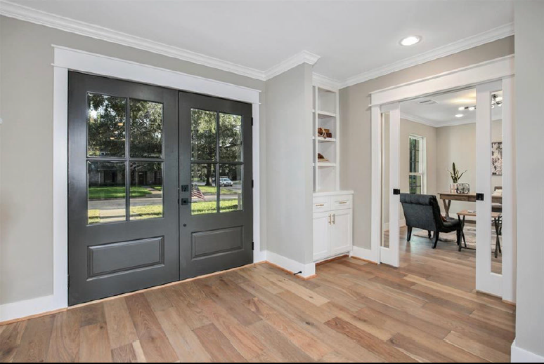 Bright entryway with gray double doors, wood floor, and open view into a dining room
