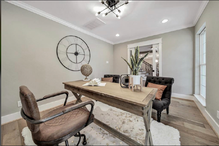 Modern dining room with rustic wood table, mixed chairs, large wall clock, and bright windows