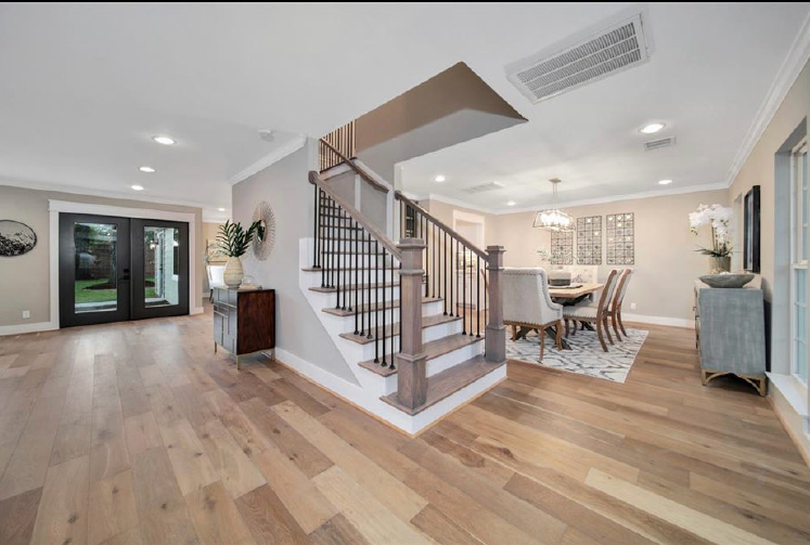 Bright open foyer with wood floors, staircase, and adjacent dining area under recessed lighting