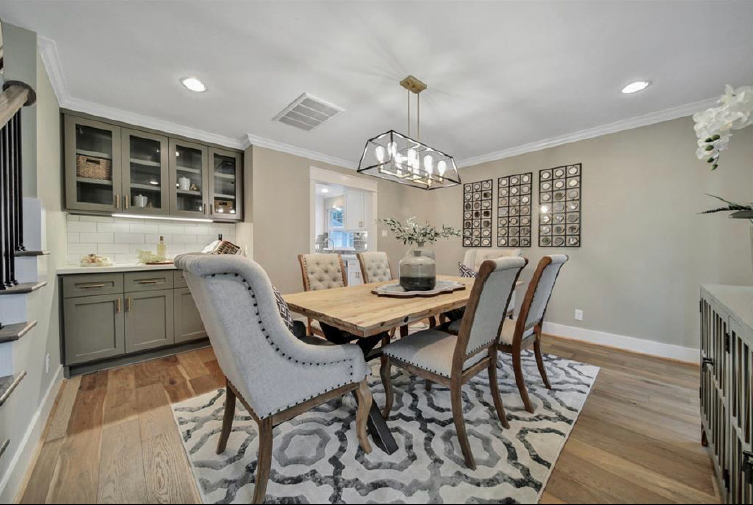 Modern dining room with gray chairs, wood table, chandelier, and patterned rug